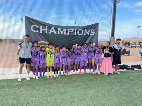 Youth soccer team in purple uniforms holding a CHAMPIONS banner at outdoor sports field