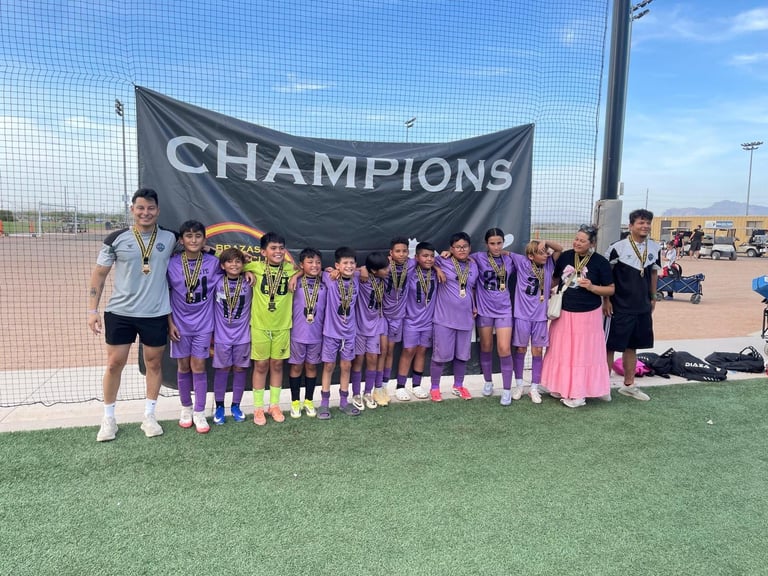 Youth soccer team in purple jerseys posing with a Champions banner on a sports field