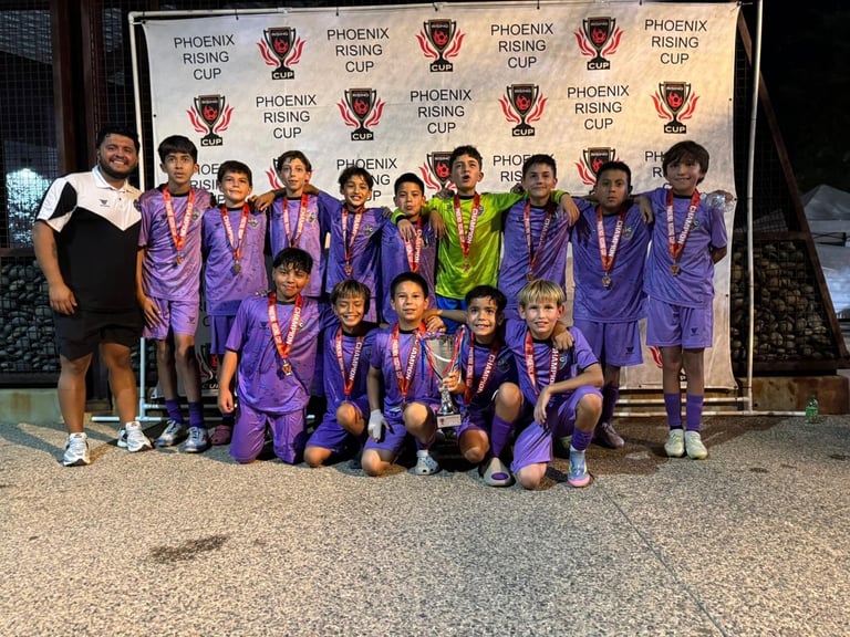 Youth soccer team in purple uniforms with medals poses in front of Phoenix Rising Cup banner