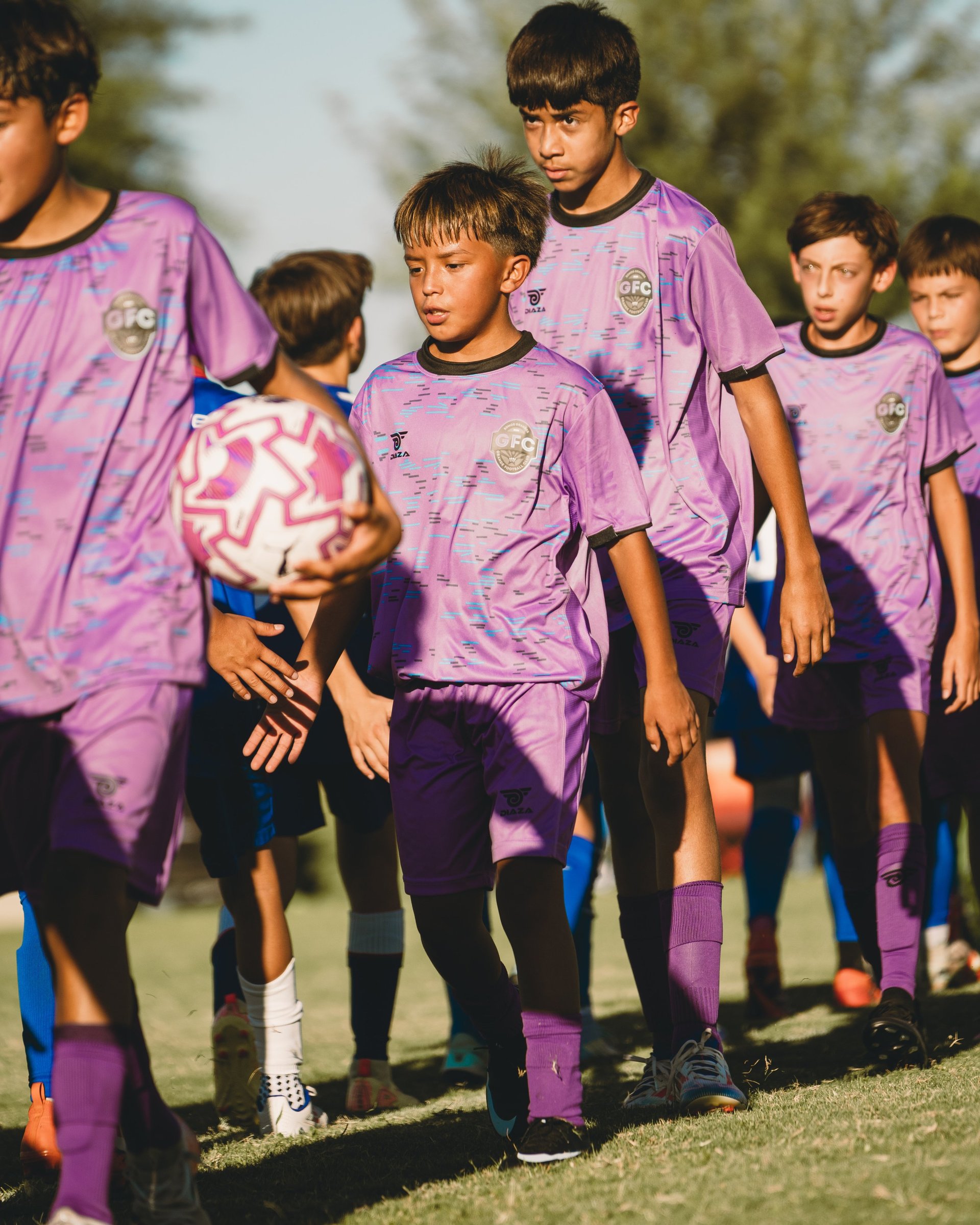 Young soccer team in purple uniforms standing together on grass field during outdoor practice or game