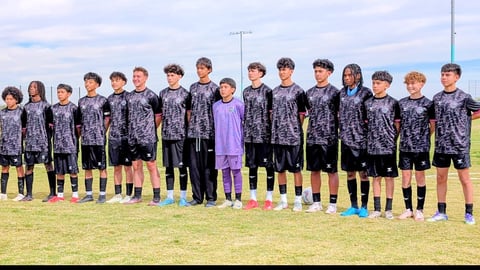 Youth soccer team in dark patterned jerseys standing in a line on a grass field