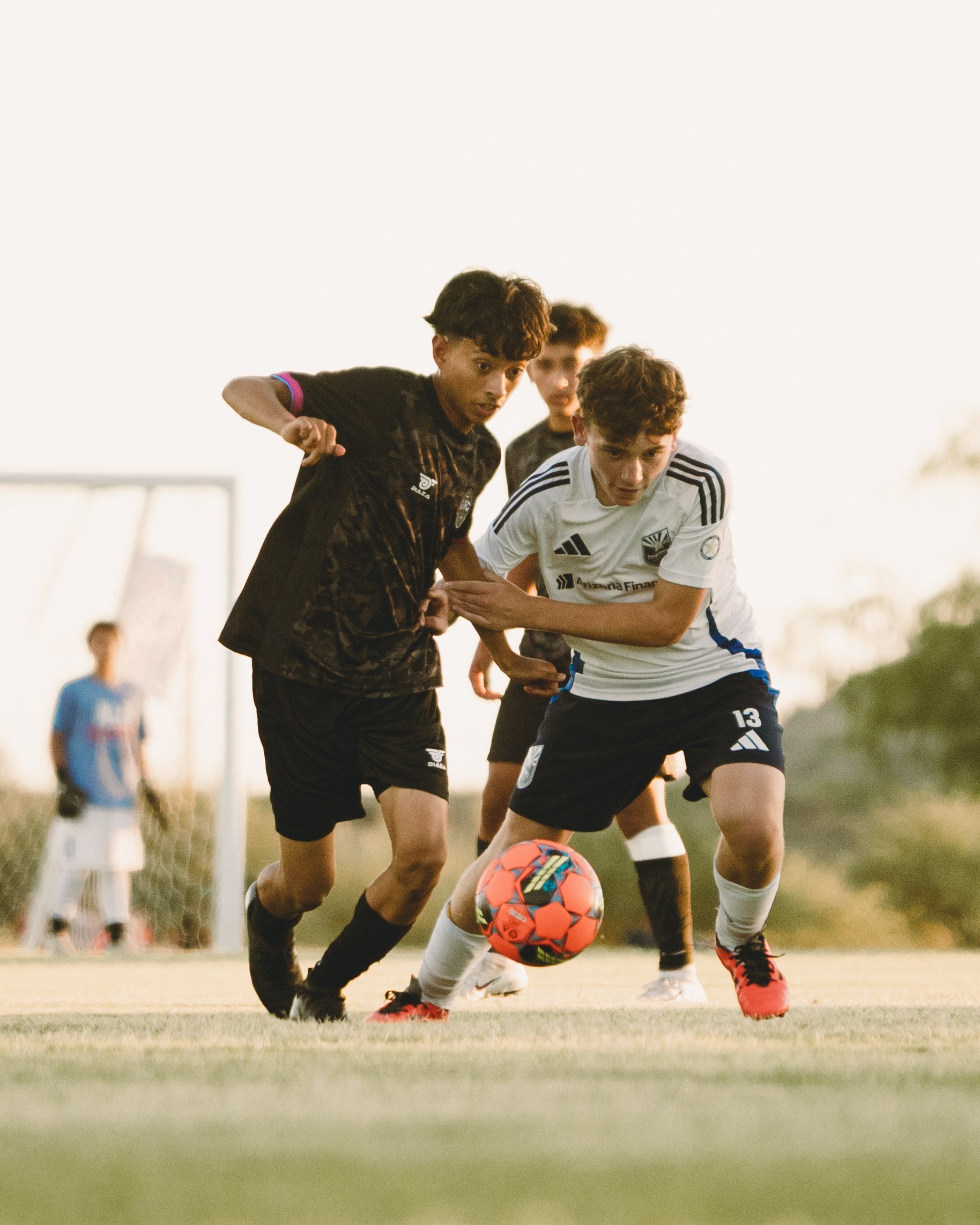 Young soccer players competing for the ball during an outdoor youth football match on a grass field